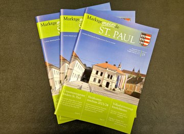 Drei Ausgaben der Gemeindezeitung auf grünem Hintergrund