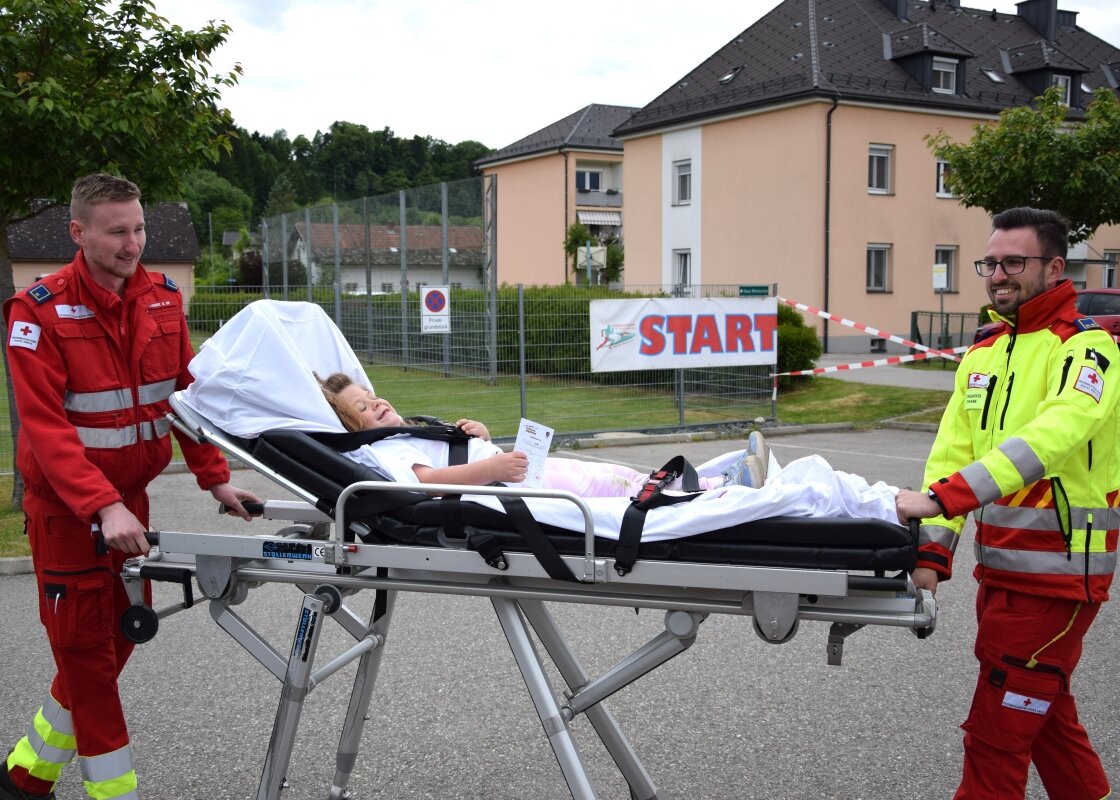 Ein junges Mädchen wird von zwei Rot Kreuz-Sanitätern auf einer Trage gefahren