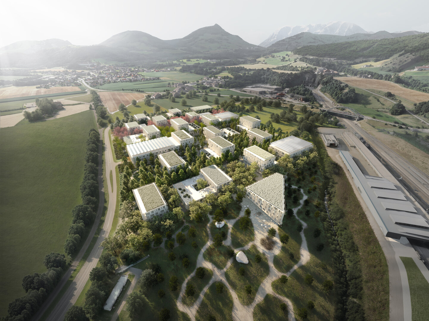 Moderne Gebäudeanlage mit begrünten Dächern in ländlicher Umgebung mit Bergen im Hintergrund.
